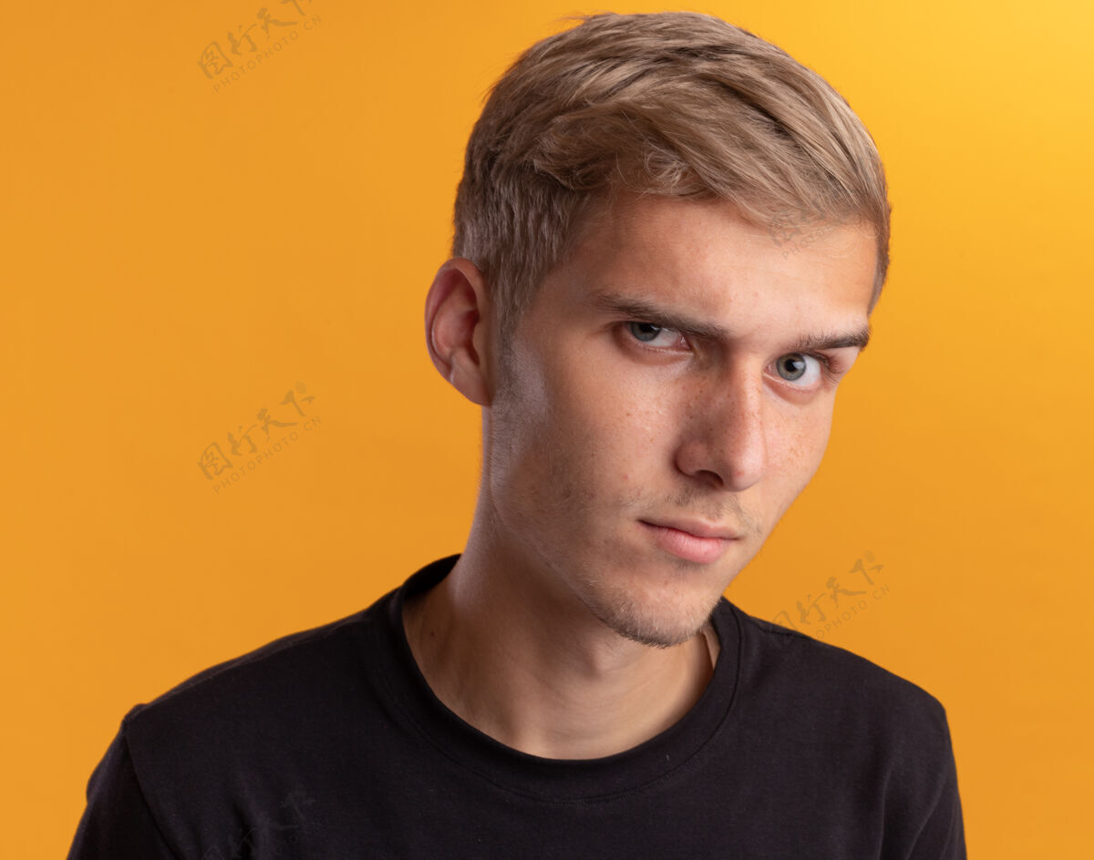 年轻自信的年轻帅哥穿着黑衬衫隔离在黄色的墙上自信小伙子衬衫