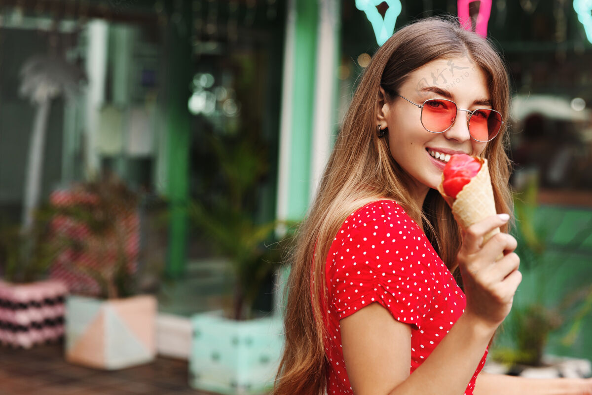 休闲浪漫的女人吃冰激凌 对着镜头微笑 享受暑假 热带岛屿之旅太阳镜街头微笑