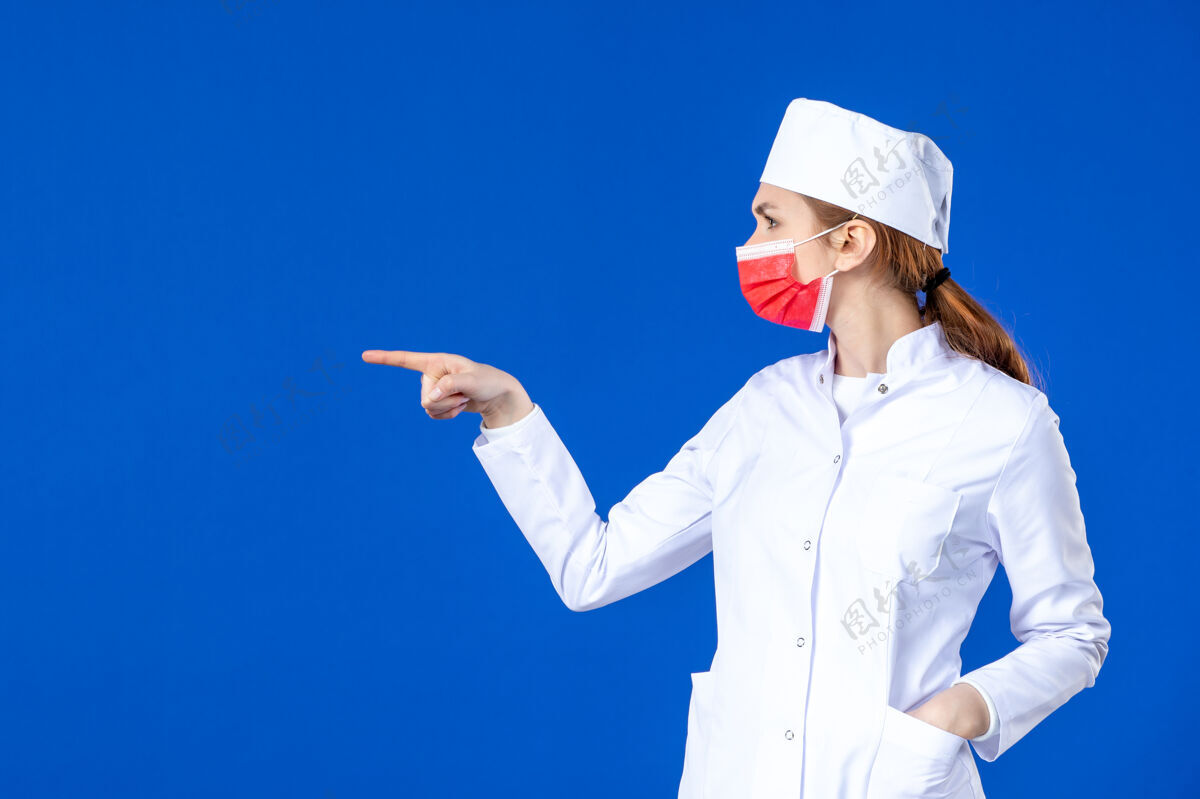 医疗正面图身着医疗服的年轻护士 蓝色墙上戴着红色防护面具疾病视图药品