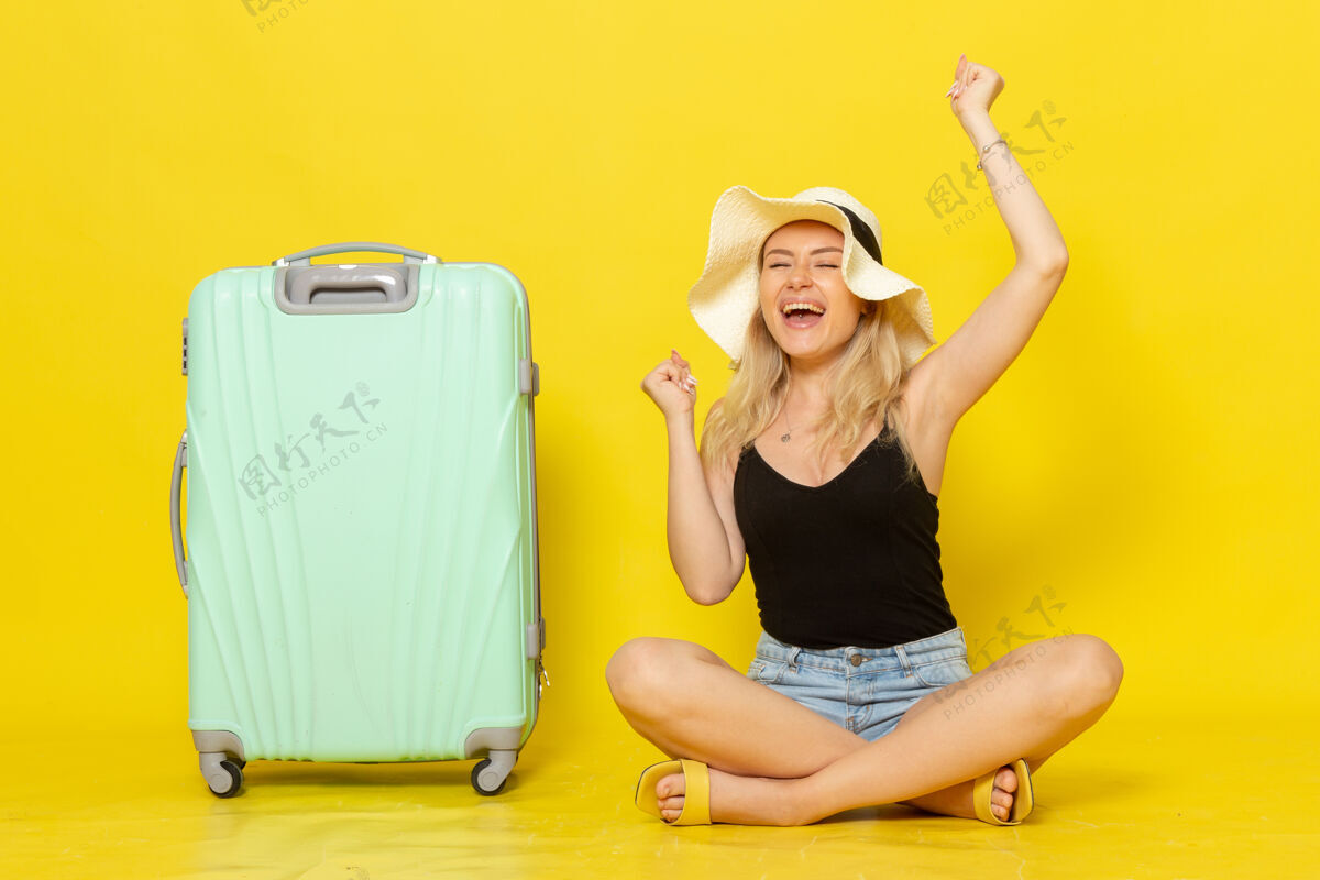 公文包正面图年轻的女性坐在黄墙上和她的绿色袋子旅行度假旅行女孩年轻人微笑一起走