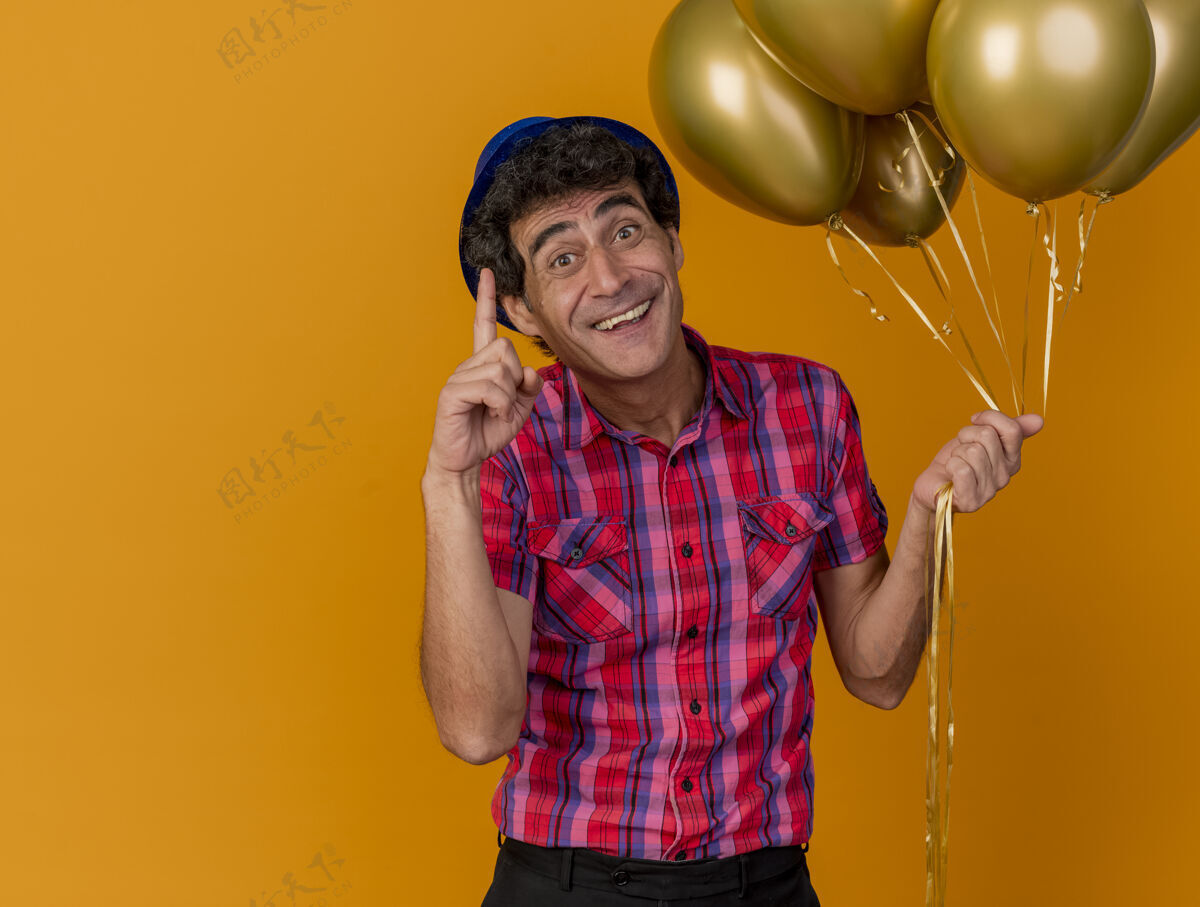 印象令人印象深刻的微笑的中年白种人党男子戴党帽举行气球举起手指孤立的橙色背景与复制空间气球握橙色