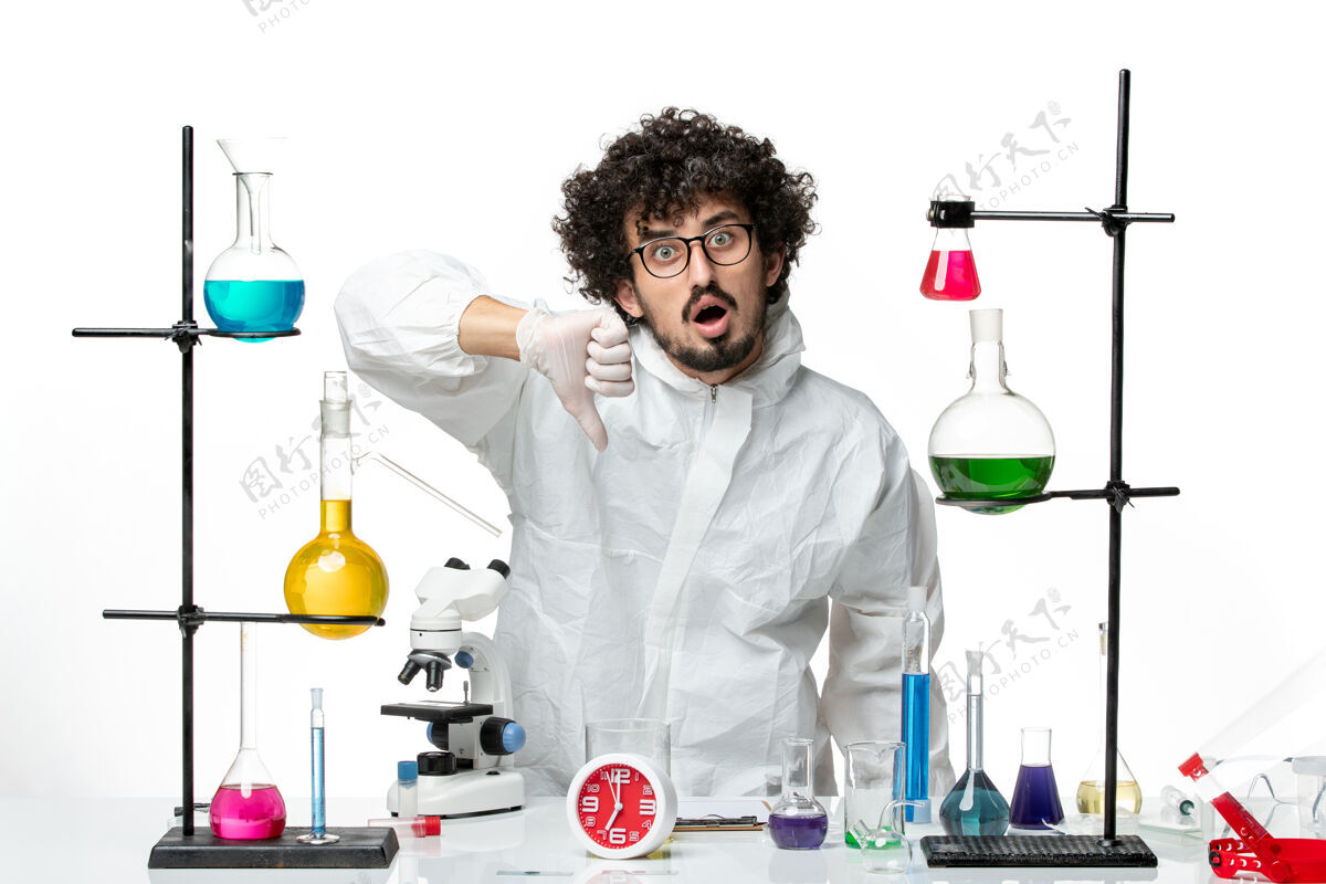 套装正面图身穿特殊套装的年轻男性科学家站在桌子周围 白色的墙上有解决方案视图溶液实验室