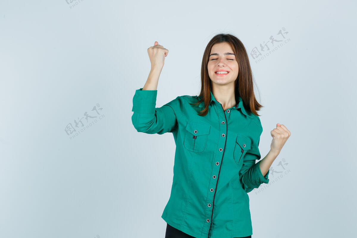 女性美丽的年轻女士在绿色衬衫中展示赢家的姿态 看起来很开心 正面视图年轻漂亮欢呼