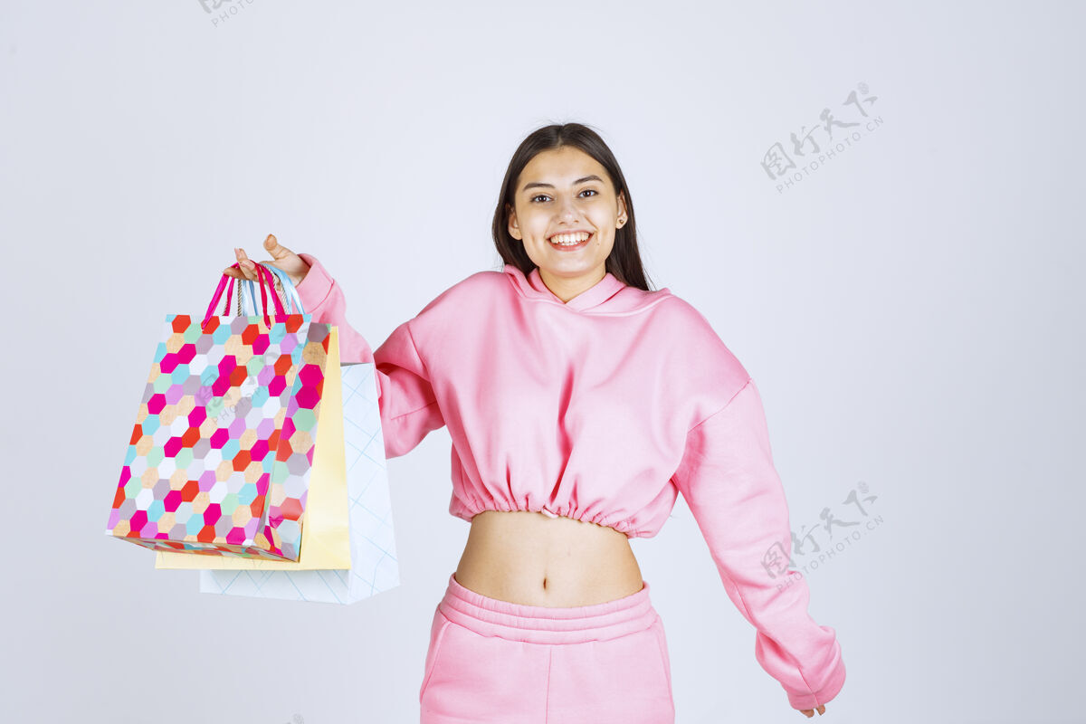 积极女孩拿着五颜六色的购物袋 看起来很兴奋女性姿势服装