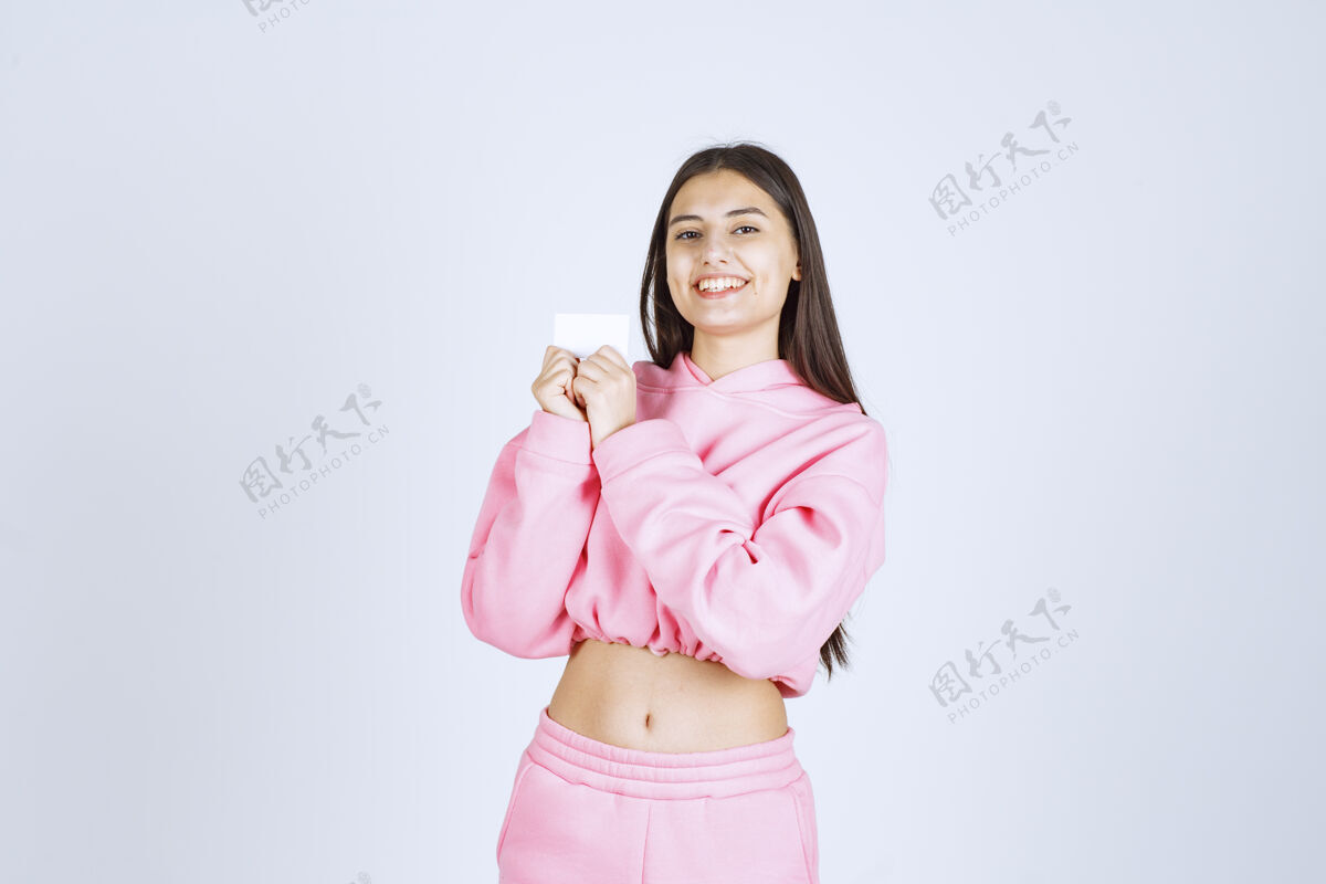 休闲穿着粉色睡衣的女孩拿着名片向她的商业伙伴介绍自己年轻人表演服装