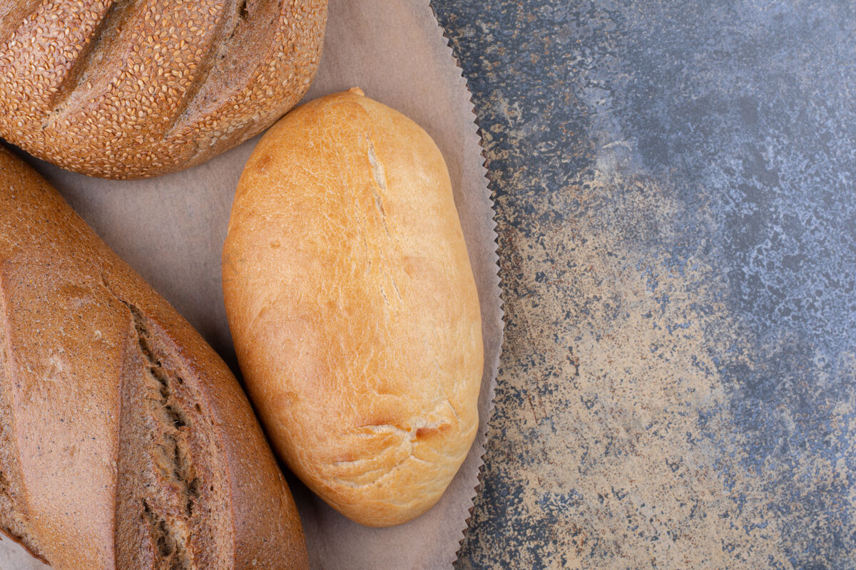 面包皮各式各样的面包类型放在大理石表面的木板上各种餐面包