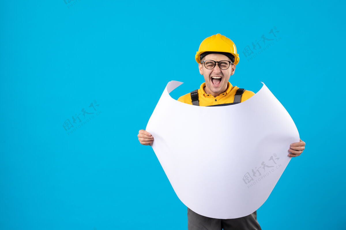 建筑商身穿黄色制服的男建筑工人的正视图 蓝色平面图职业施工工作