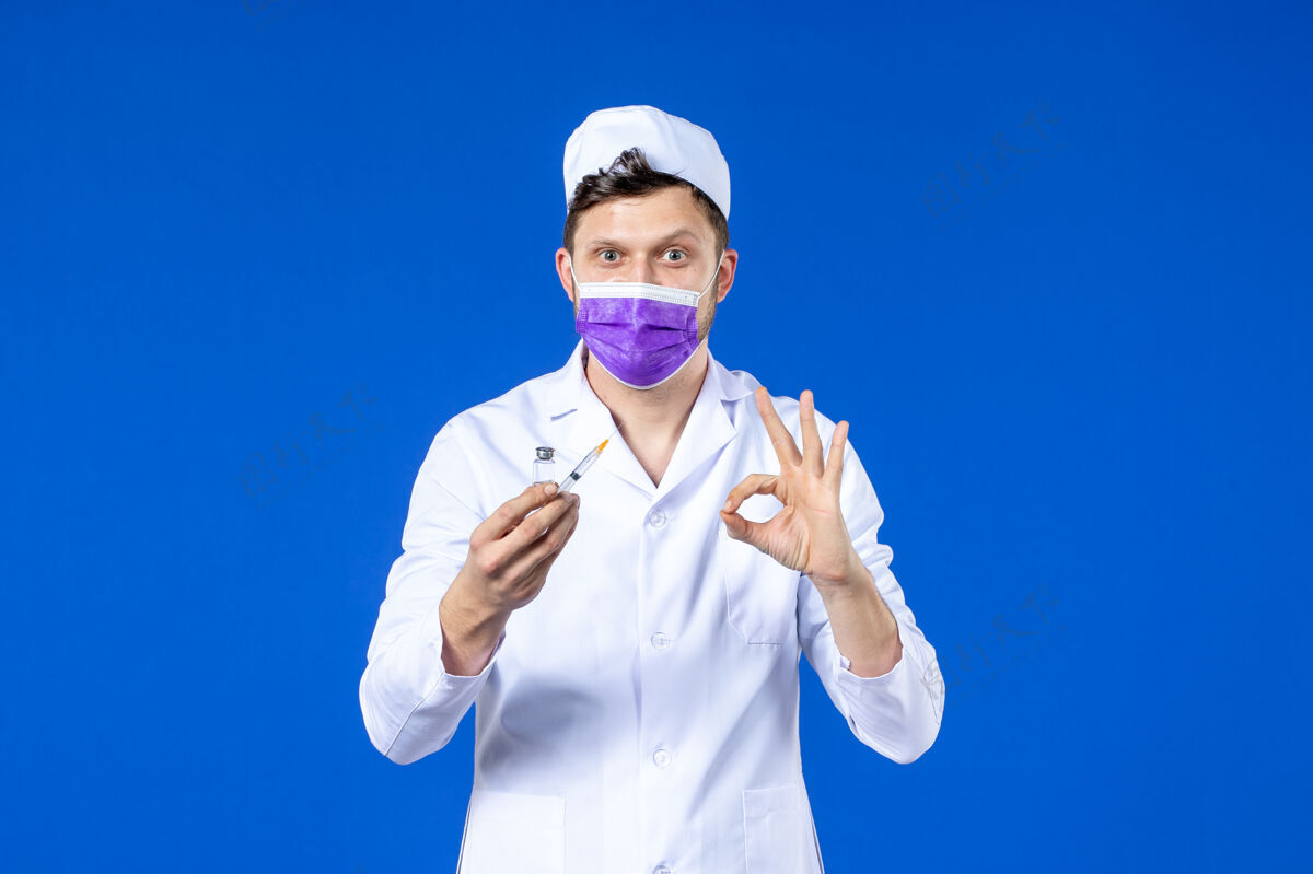 医院男医生的前视图 穿着医疗服 戴着蓝色的注射和疫苗面罩男医生大流行衣服
