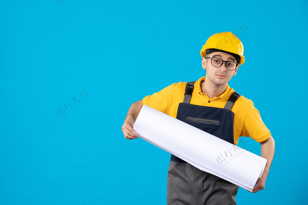 工程师身穿黄色制服的男建筑工人正面图蓝色阅读平面图制服承包商阅读