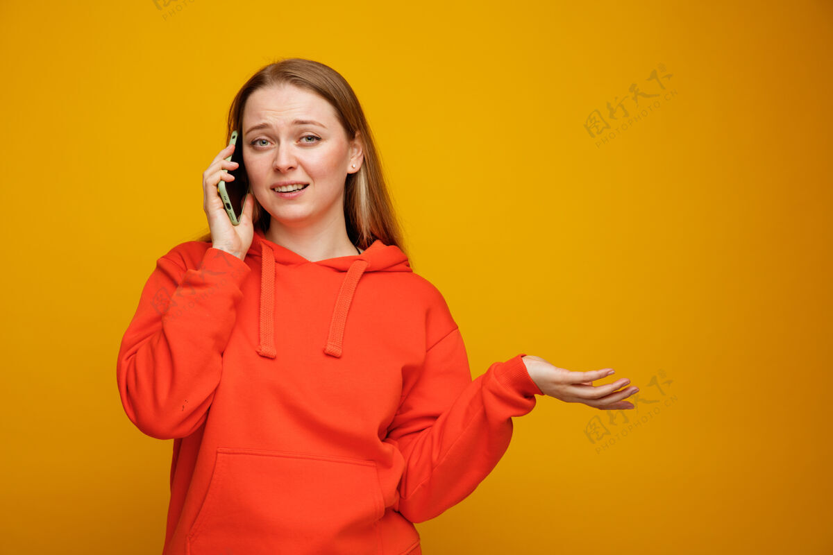 女人笨手笨脚的金发女郎在电话里空手说话电话橙色秀