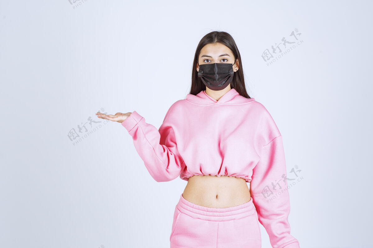 手术穿着粉色睡衣和黑色面具的女孩指着左边护理制服妇女