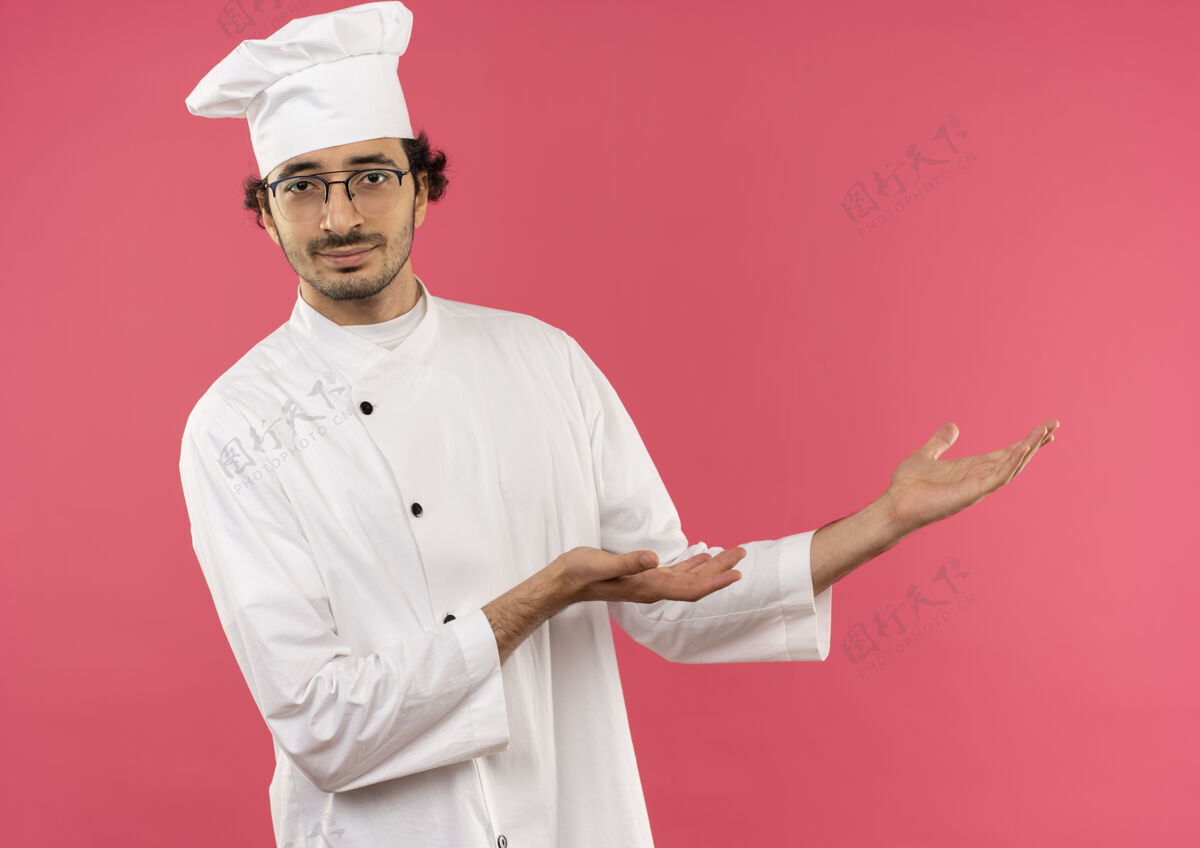 眼镜年轻的男厨师穿着厨师制服 戴着眼镜 双手放在一边粉红手穿