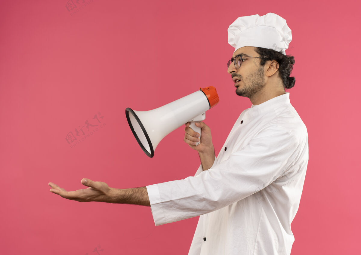 厨师看着身边困惑的年轻男厨师 穿着厨师制服 戴着眼镜 用扩音器说话 手拉着手年轻粉色扩音器