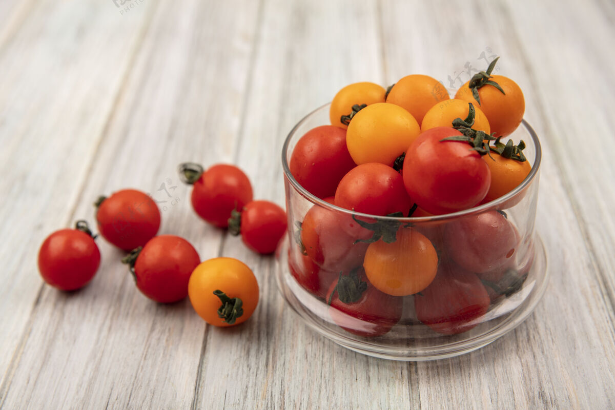 碗新鲜的红色西红柿在一个灰色的木制表面玻璃碗顶视图玻璃蔬菜饮食