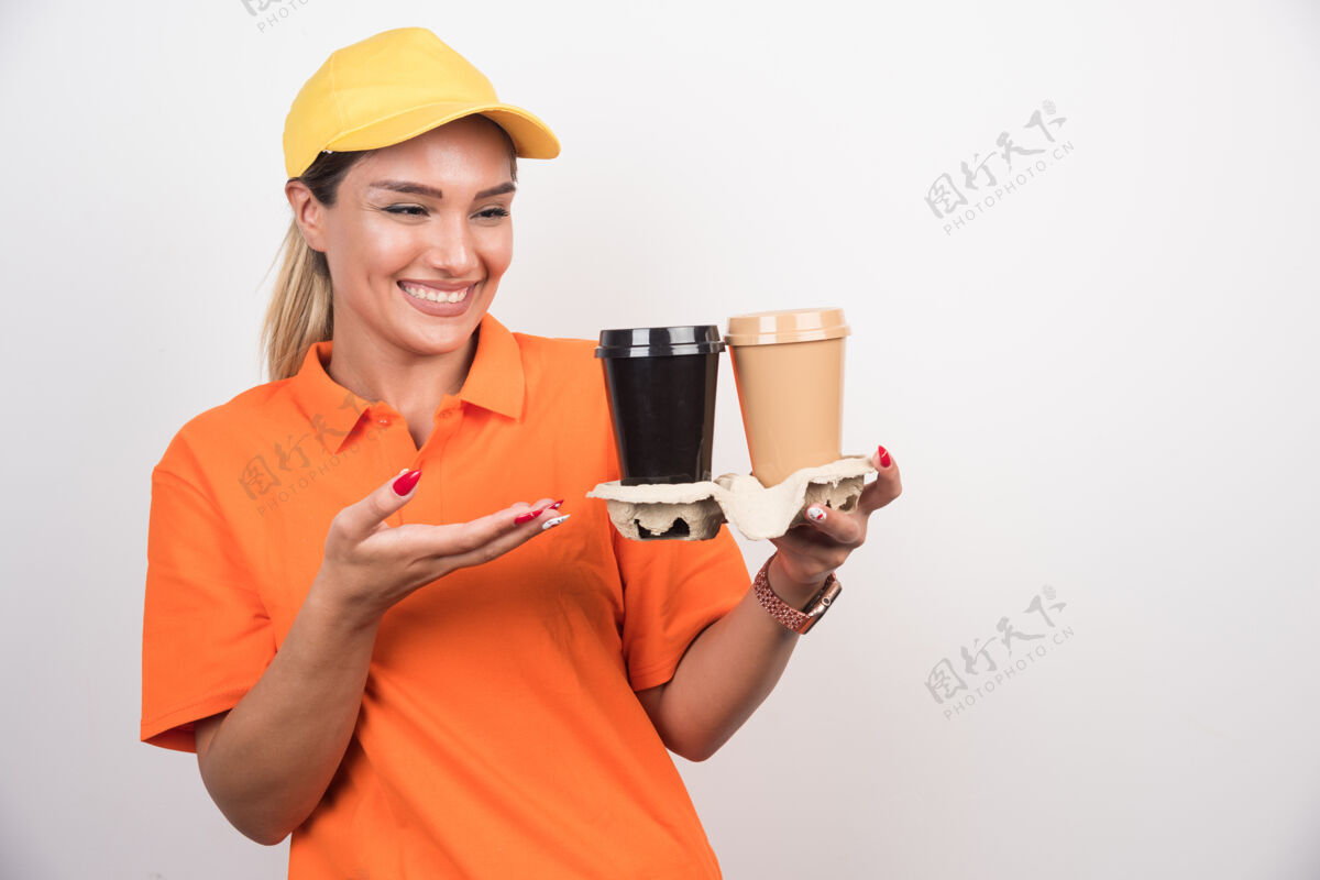 送货金发女信使指着白墙上的两杯咖啡快递订单塑料杯