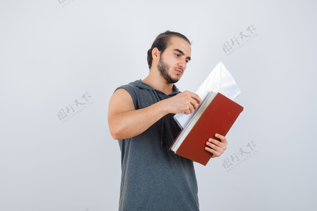 人年轻的男性穿着无袖连帽衫看着一个文件 看起来很专注前视图活动健美健康