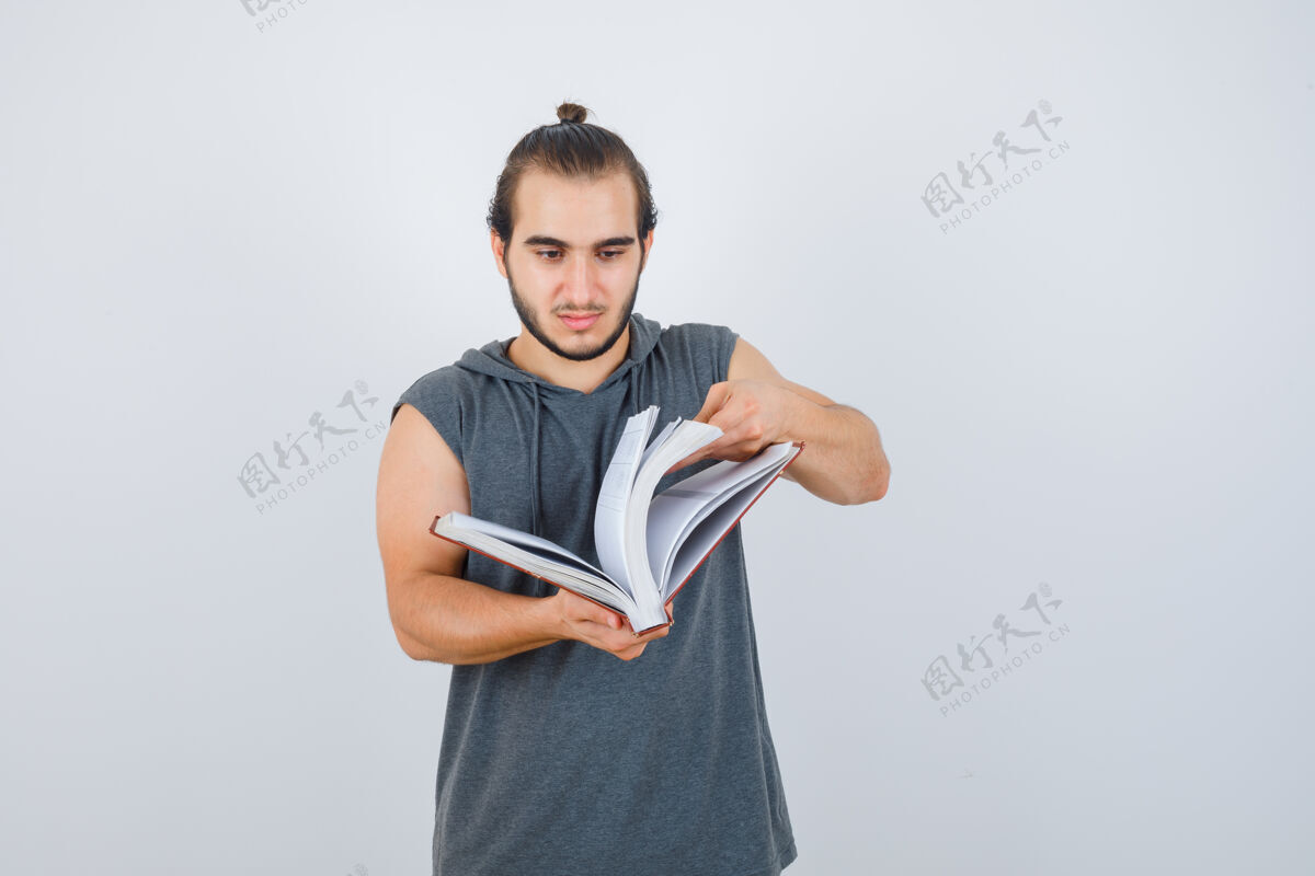 决心穿无袖连帽衫的年轻男性翻阅书籍 看起来自信 前视图男人商业