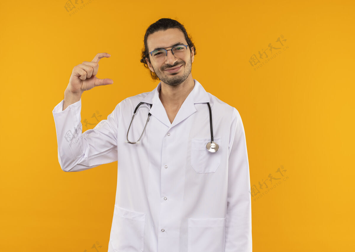 医生年轻的医生戴着医用眼镜 穿着医用长袍 戴着听诊器 假装拿着什么东西穿男性年轻