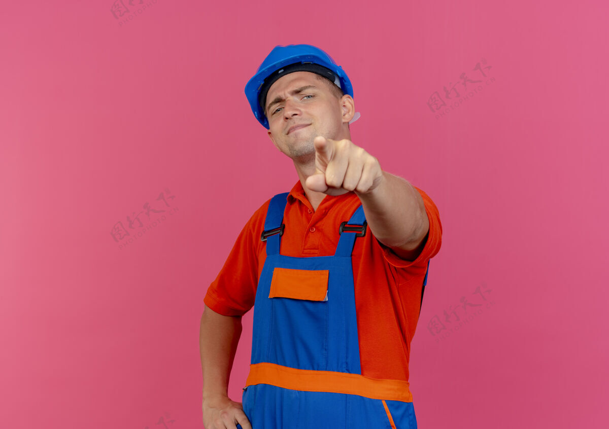 年轻自信的年轻男性建筑工人穿着制服 戴着安全帽向你展示姿势穿着男人安全