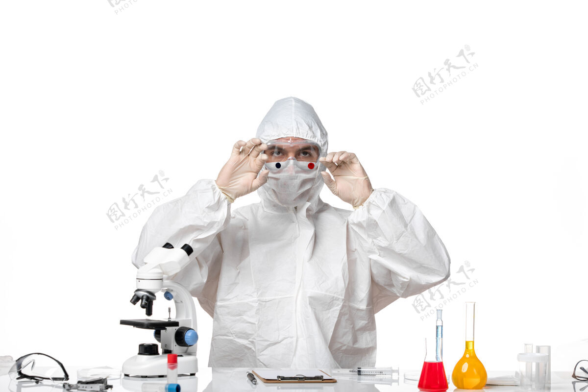到期正面图：男医生穿着防护服 戴着面罩 因为covid拿着烧瓶在浅白色的空间里病毒防护套装