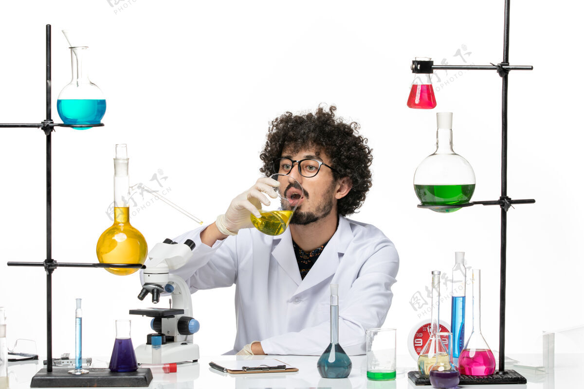 实验室正面图：男化学家穿着医疗服在白色空间里饮用水实验室外套医生外套