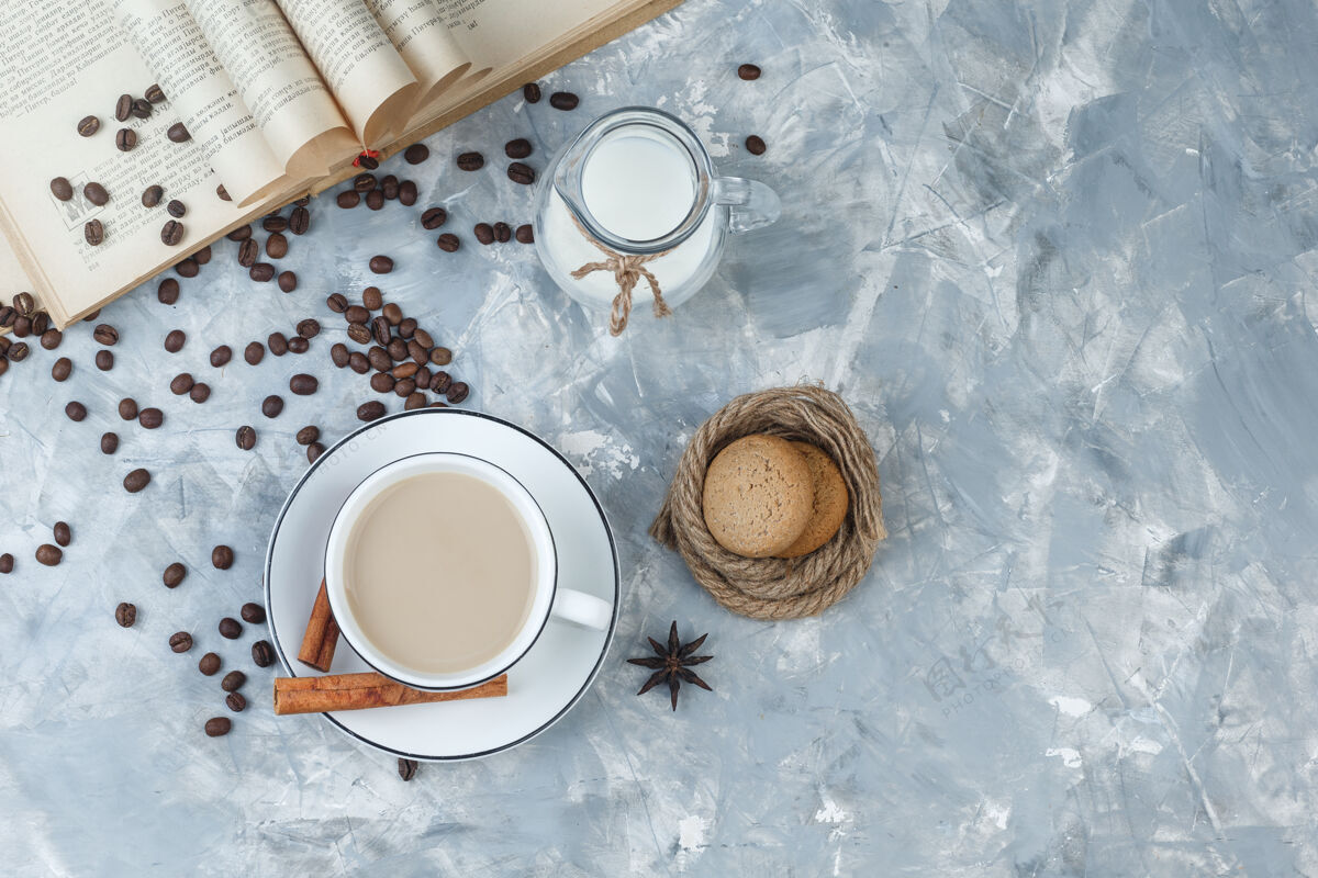 卡布奇诺一些咖啡与饼干 咖啡豆 书 牛奶 香料在一个灰色灰泥背景 顶视图杯热人早餐
