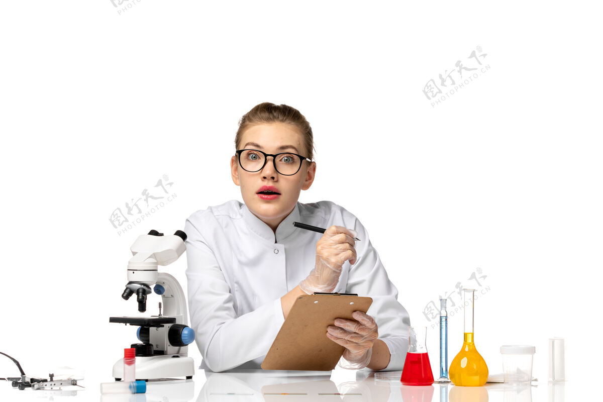 办公室前视图穿着白色医疗服的女医生在空白处写笔记笔记写作病毒