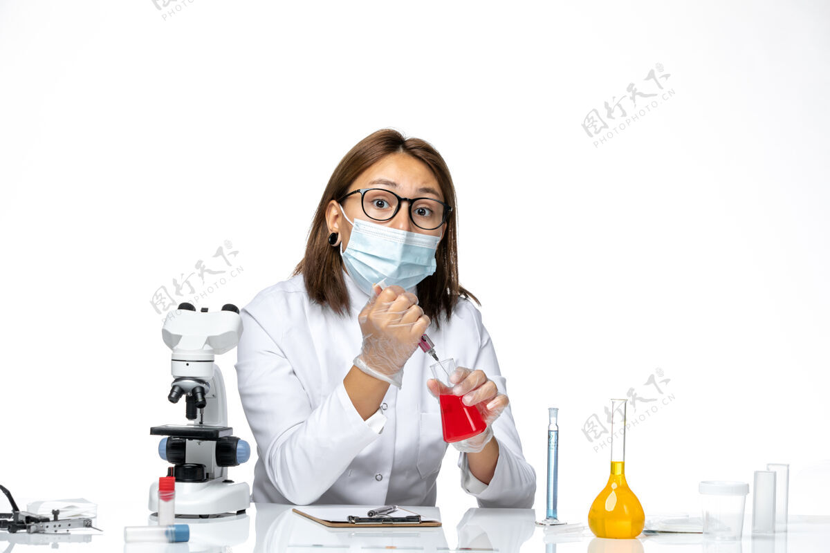 专业正面图：女医生穿着白色医疗服 戴着面罩 因为在工作过程中戴着隐形眼镜 在浅白色的空间里女医生病毒面具