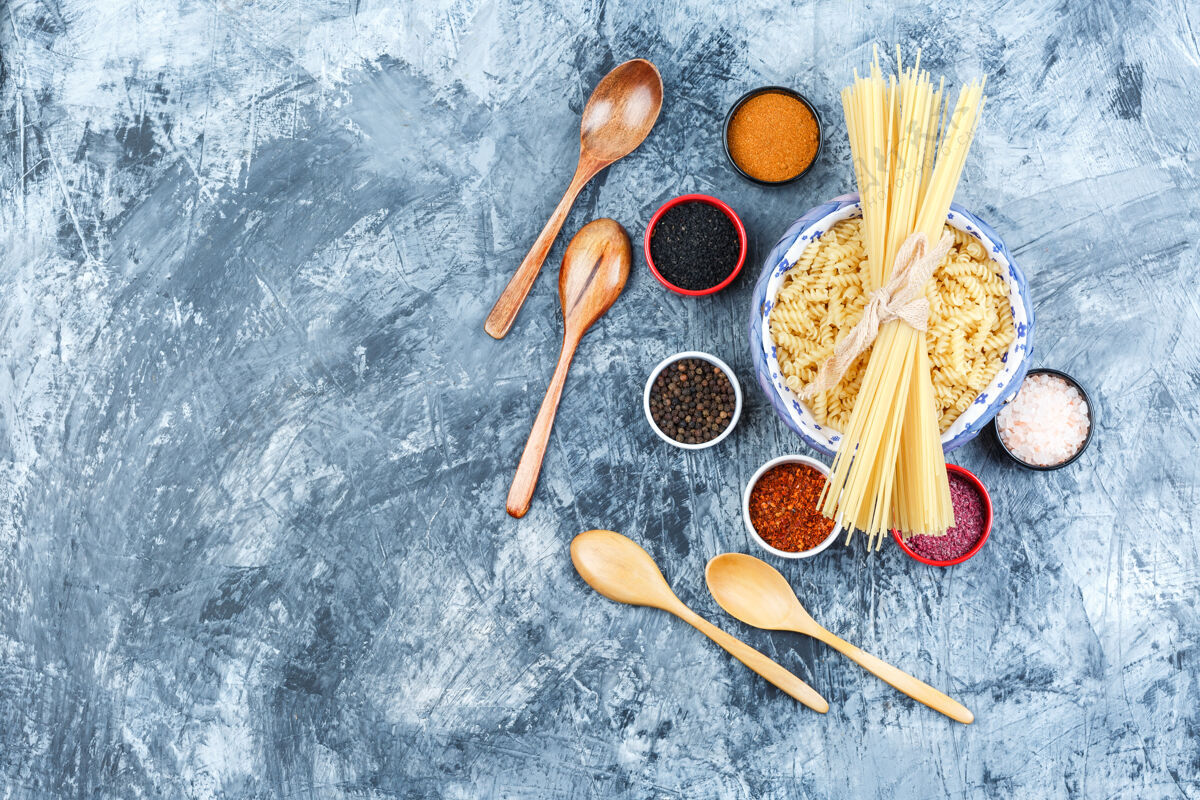 地中海一些意大利面配意大利面 香料 木制汤匙放在灰色灰泥背景的碗里 顶视图香料食物美食