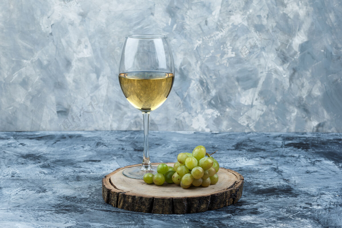 玻璃一些绿色的葡萄和一杯葡萄酒在肮脏的石膏和木片背景上 侧视图木材串营养