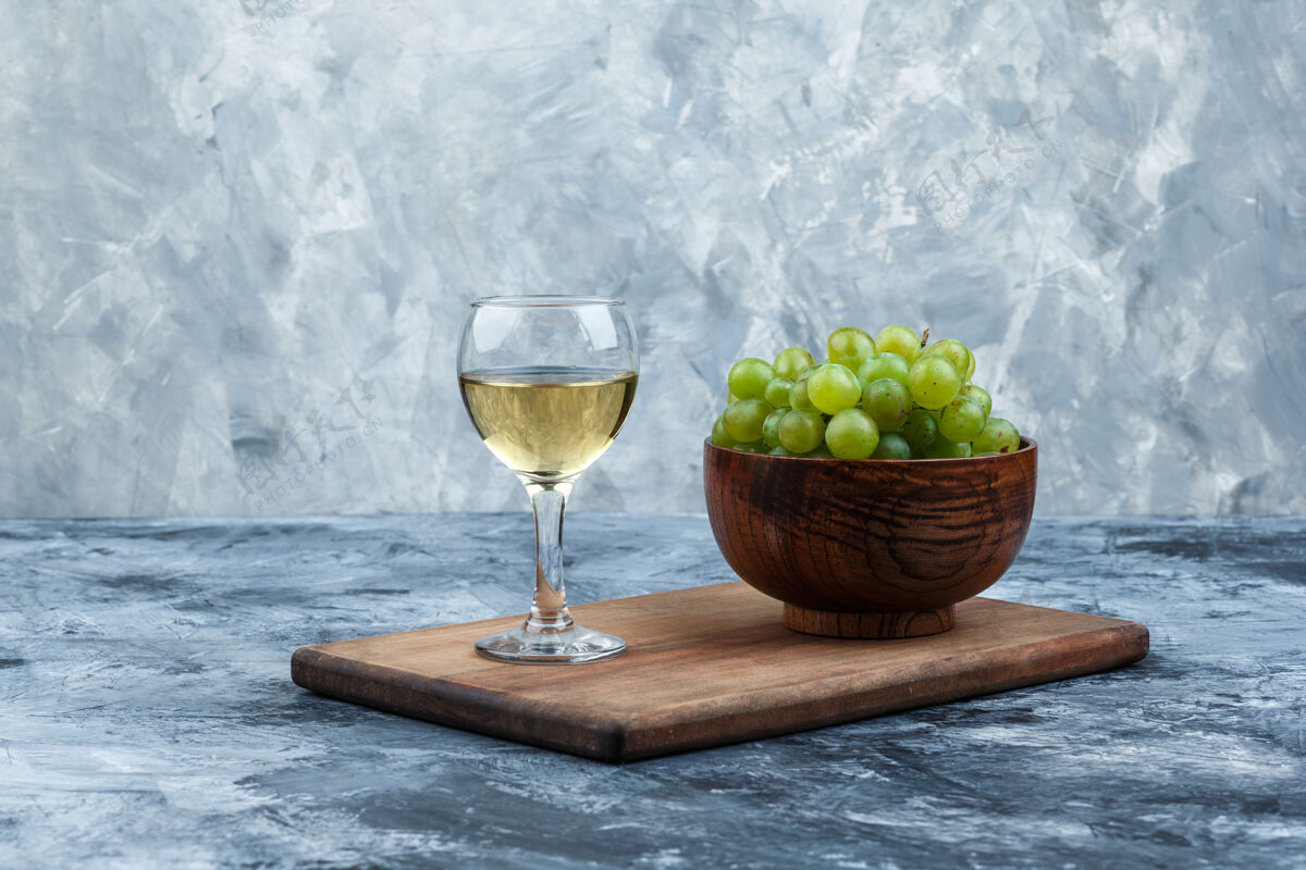 玻璃把一碗白葡萄 一杯威士忌放在深蓝色大理石背景的砧板上水平大理石浆果饮食