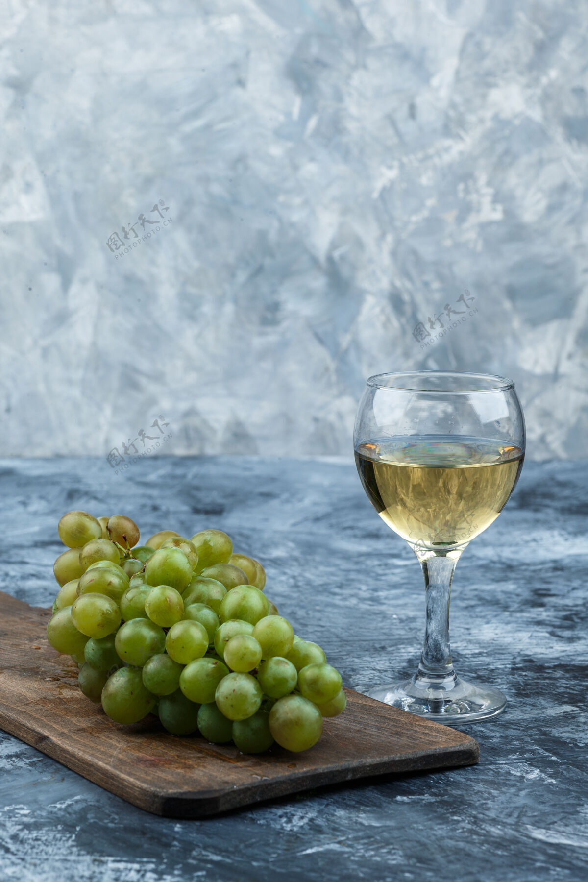 大在深蓝色大理石背景上的砧板上放一杯葡萄酒和白葡萄特写镜头农业健康叶子