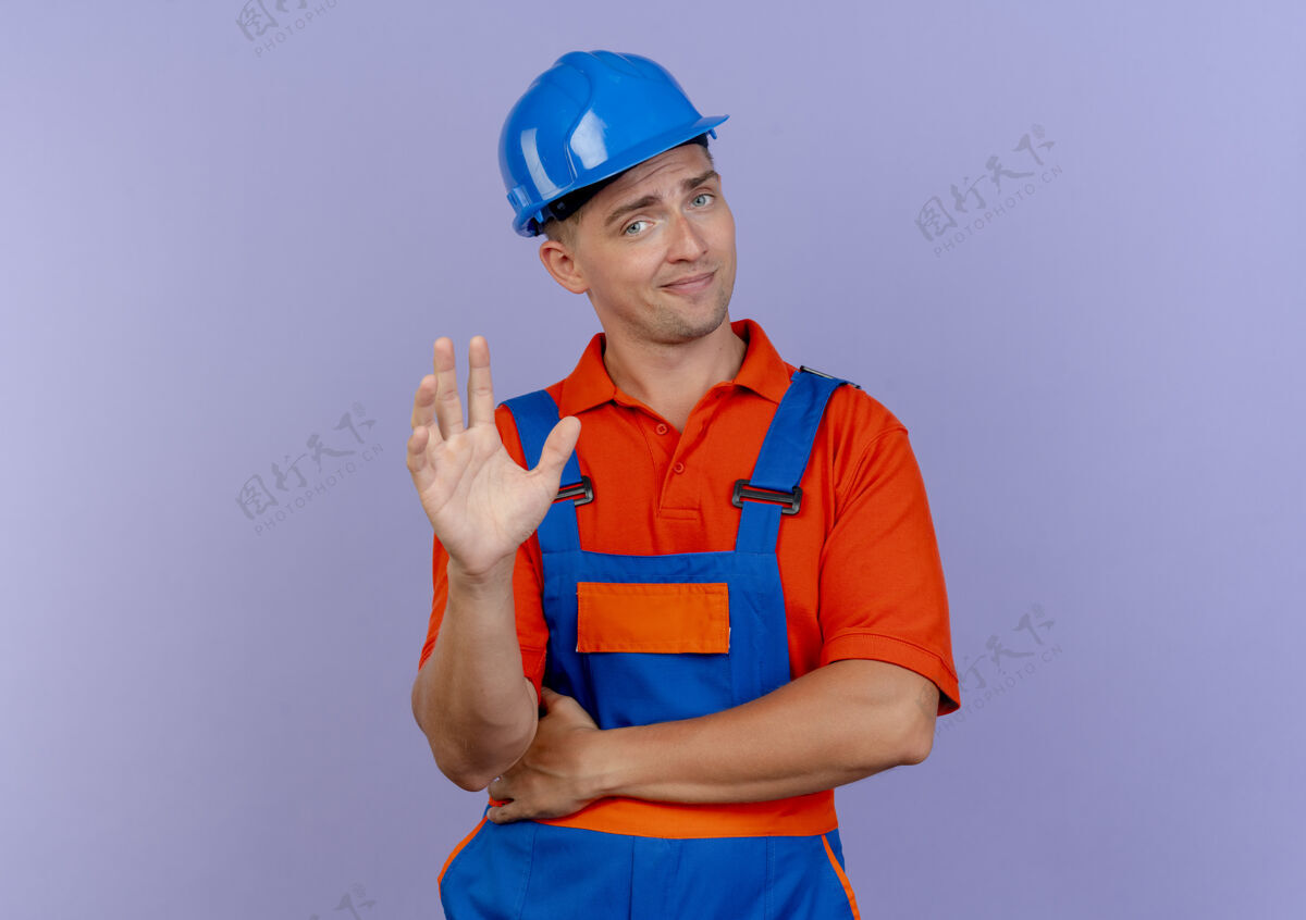 印象令人印象深刻的年轻男子建设者穿着制服和安全帽举手男性建筑工人穿着