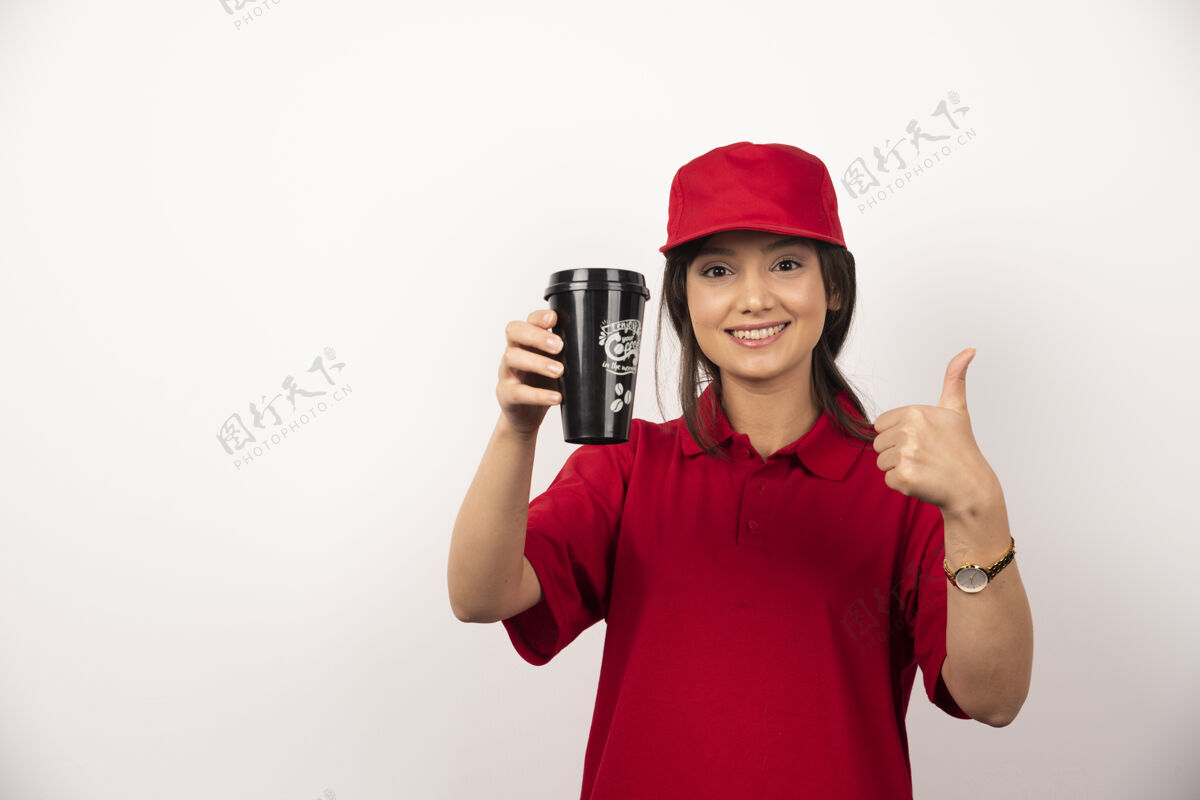 微笑穿着红色制服的女人在白色背景上展示一杯咖啡杯子女性女人