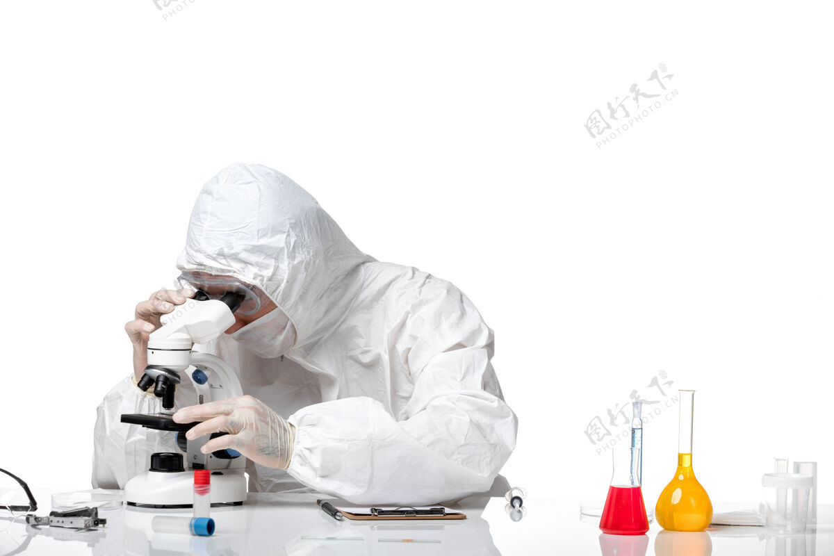 修理工正面图：男医生穿着防护服 戴着面罩 在空白处使用显微镜套装病毒显微镜