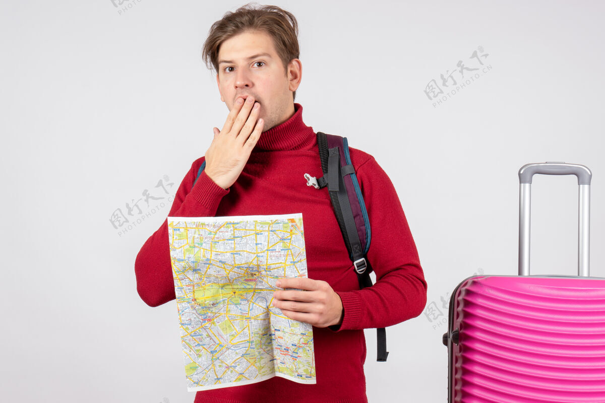假期男性游客的正面图 白色墙上有背包和地图地图微笑快乐