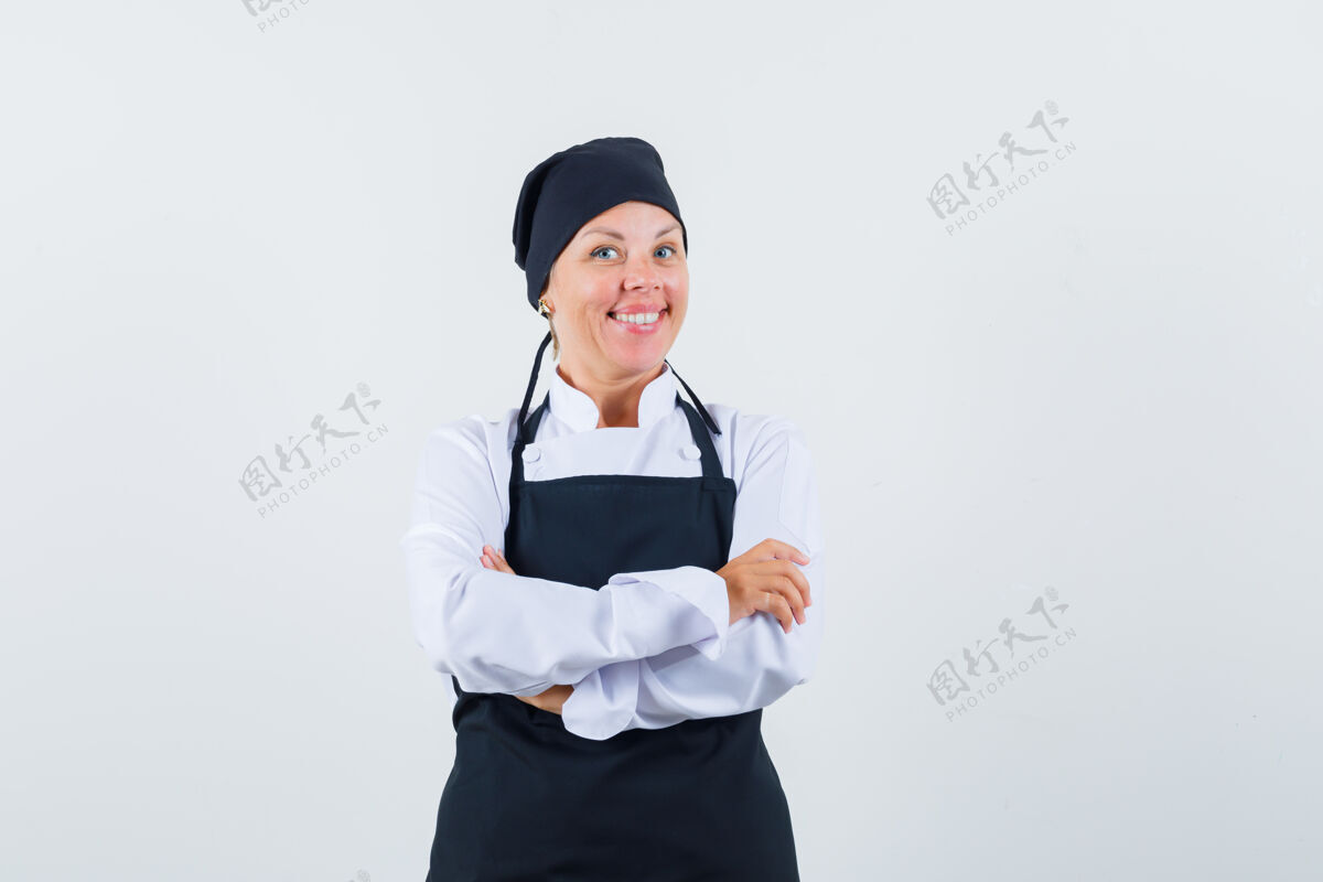 漂亮女厨师穿着制服 交叉双臂站在那里 围着围裙 看上去很开心 正对着前方可爱肖像护理