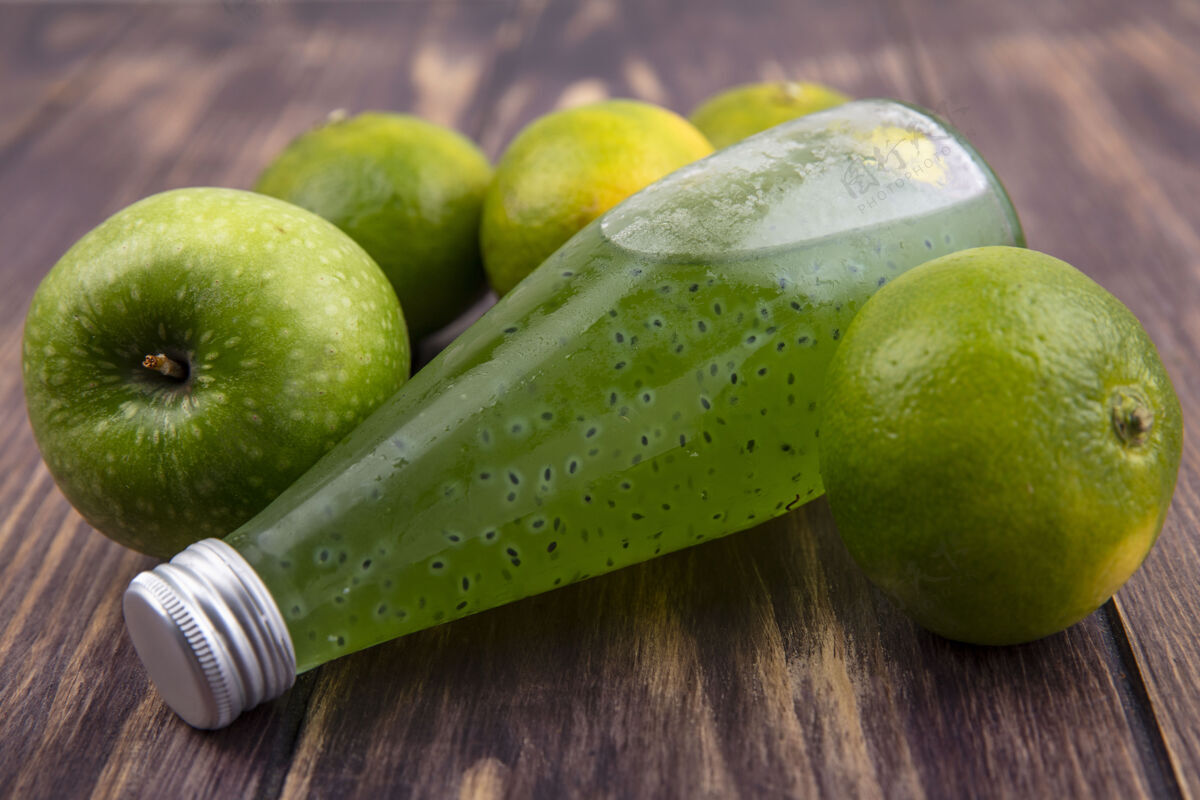 果汁前视图果汁瓶与绿色的橘子和苹果在木墙上木头瓶子苹果
