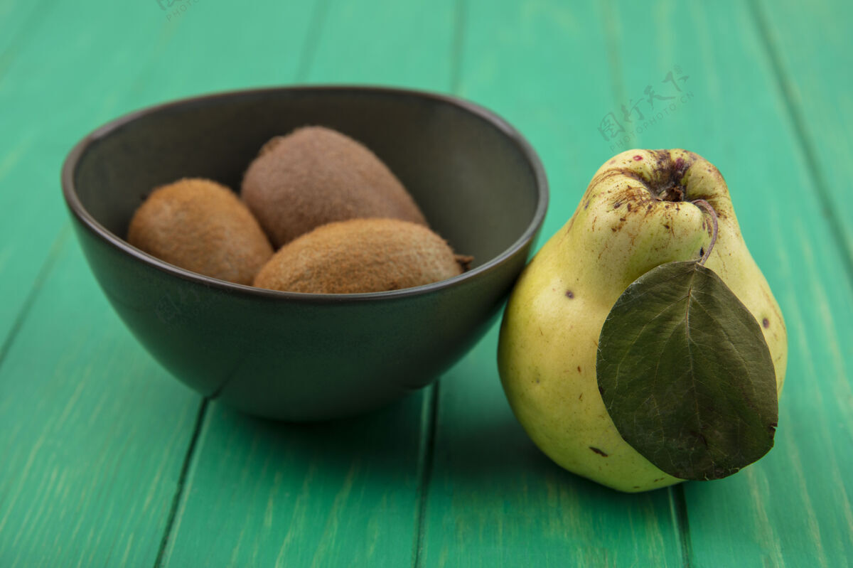 水果前视图猕猴桃在碗里和梨在绿色的墙上碗视野猕猴桃