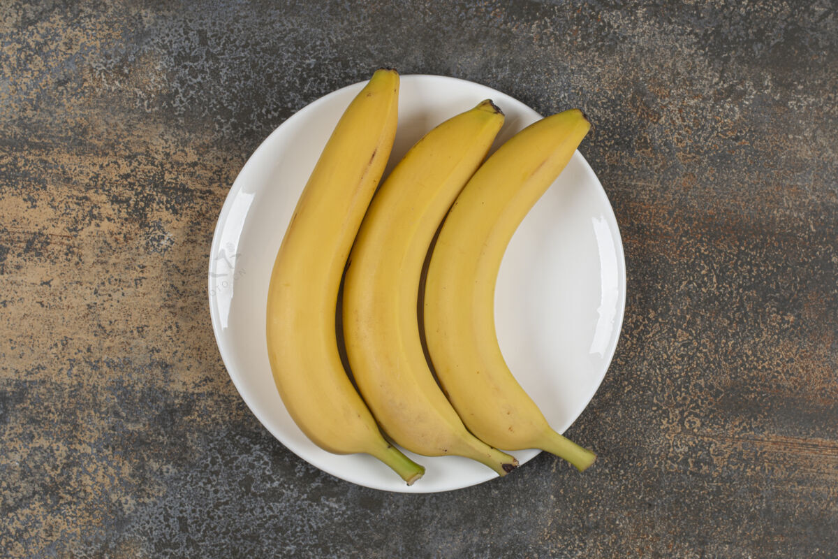 健康白盘子里有三个熟香蕉农业新鲜香蕉