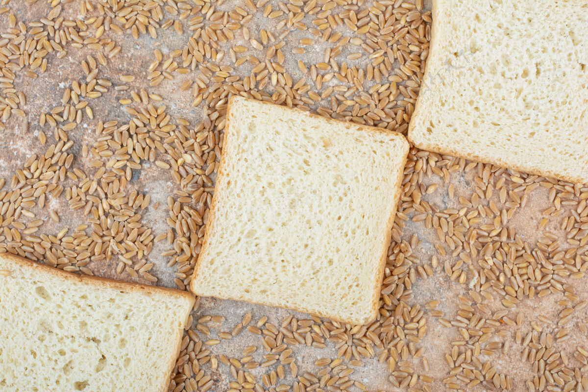 新鲜白面包片和大麦在大理石表面大麦切片小麦