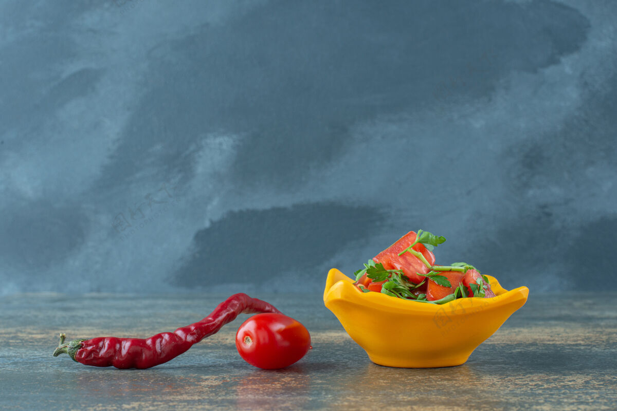 美味黄色盘子里的美味沙拉 大理石背景上有胡椒和西红柿胡椒健康美味