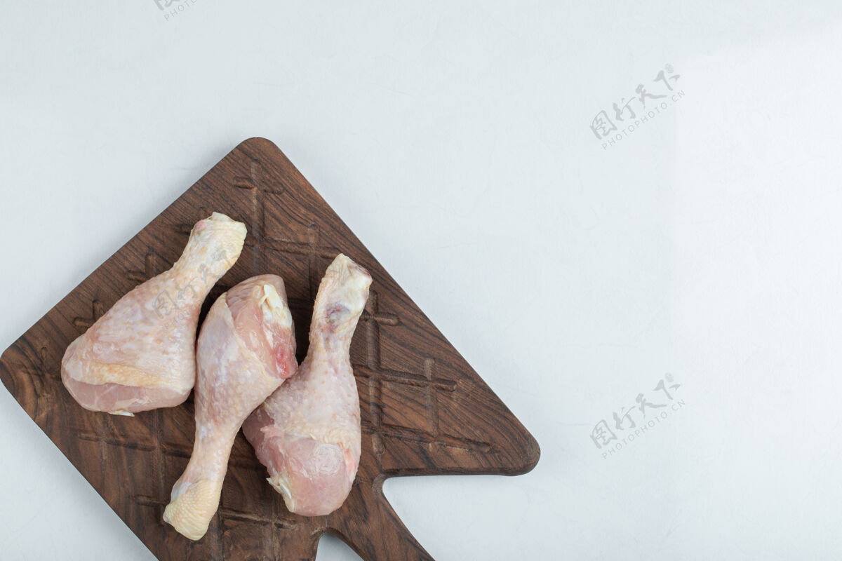 肉新鲜鸡肉放在白色背景的木制砧板上生的腿家禽