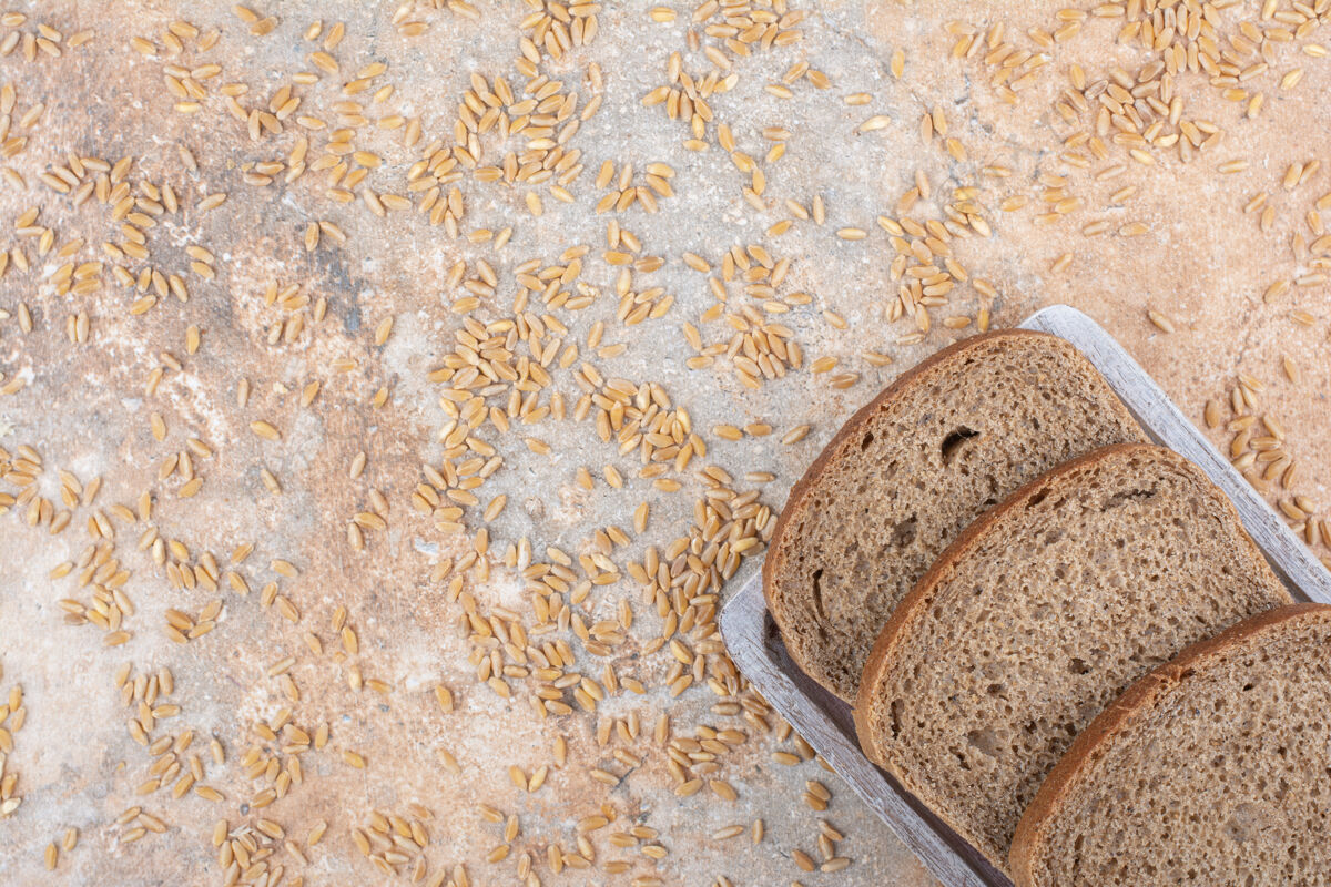 面包黑面包片和大麦粒在大理石表面新鲜谷物切片