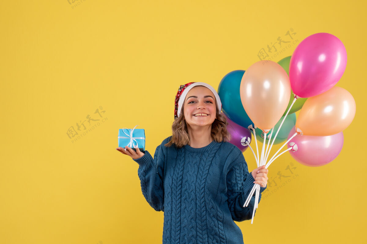庆祝手持小礼物和黄色气球的年轻女性黄色生日年轻女性