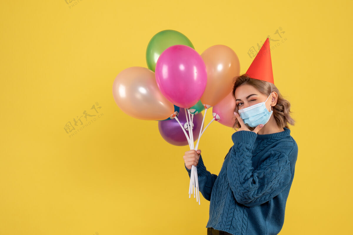 聚会戴着黄色面具手持彩色气球的年轻女性庆祝乐趣生日