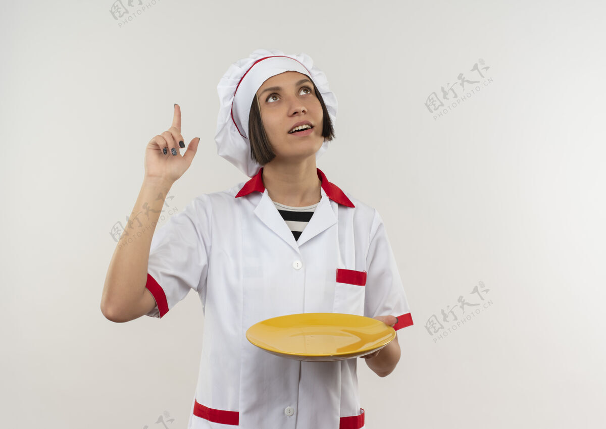 盘子令人印象深刻的年轻女厨师在厨师制服举行盘子看 并指出孤立的白色与复制空间空间拿着女