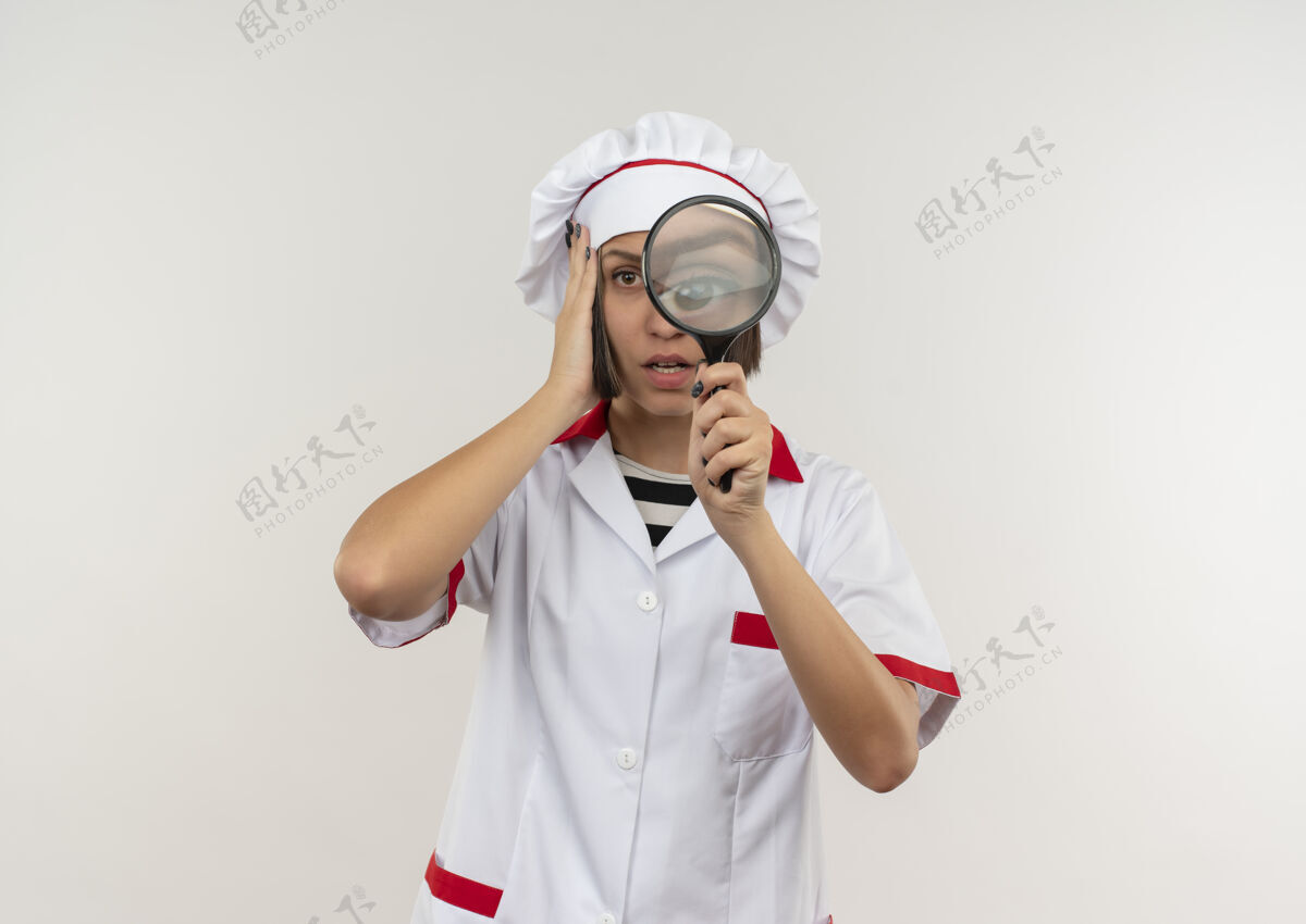 头令人印象深刻的年轻女厨师穿着厨师制服手持放大镜 手放在头上 隔离在白色的复制空间女性持有空间