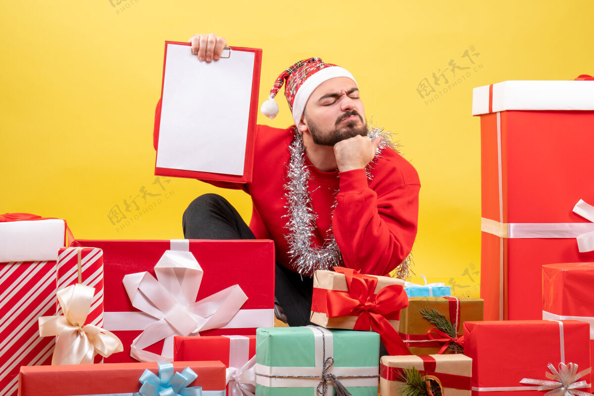 圣诞节正面图年轻男性围坐在礼物上 黄色背景上有便条礼物漂亮情感