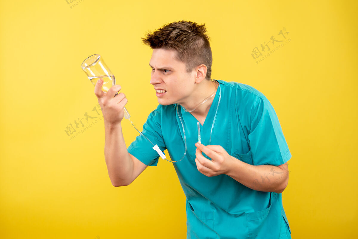 滴管正面图身穿医疗服的年轻男医生拿着黄色背景上的滴管成人人背景